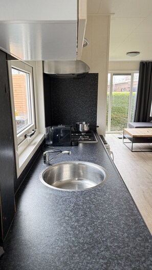 A modern kitchen with a stainless steel sink, a stove, and a window.