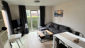 Una sala de estar moderna con un sofá, una mesa de comedor y un televisor.