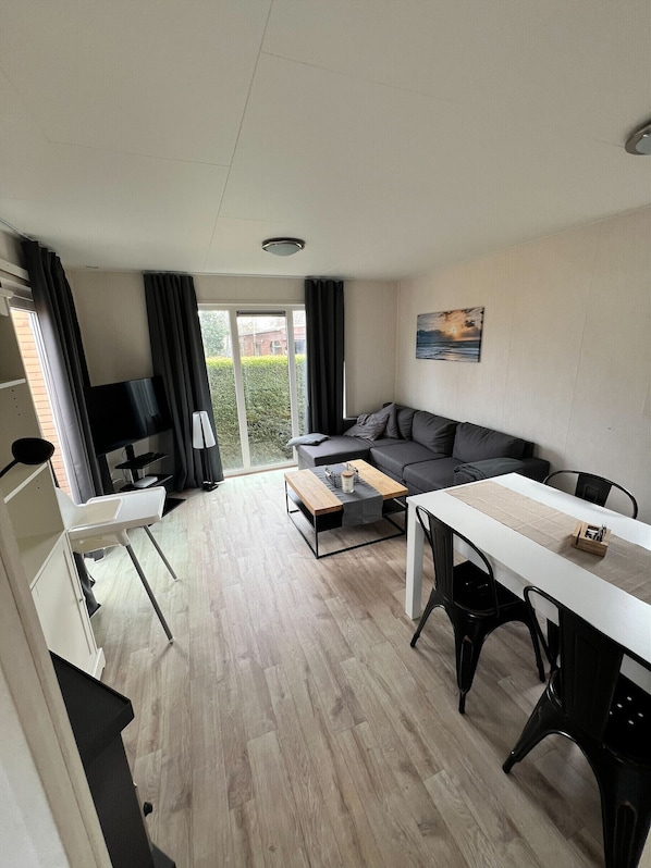 A modern living room with a sofa, a dining table, and a TV.