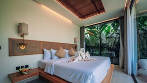 Una habitación de hotel moderna con una cama grande, cabecera de madera, mesita de noche con frutero y vistas a exuberante vegetación a través de amplias ventanas.