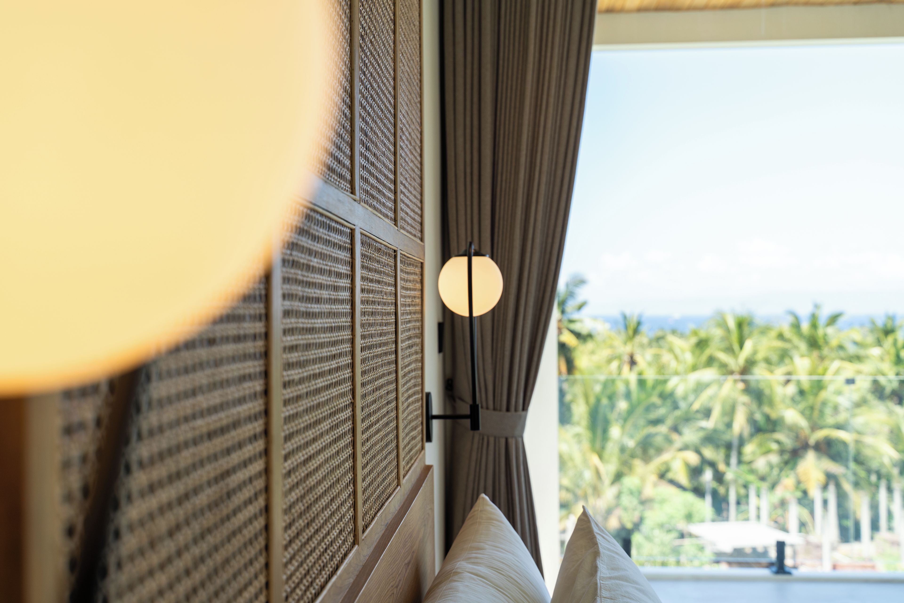 Una habitación con vista a palmeras y una masa de agua.