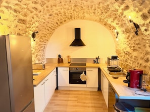 Een kleine keuken met een stenen muur, een moderne oven, een broodrooster en een koffiezetapparaat.