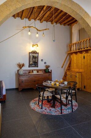 Ein Essbereich mit einem runden Tisch, Stühlen und einer rustikalen Holzbalkendecke.