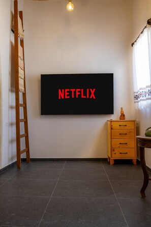 Ein Zimmer mit einem an der Wand befestigten Flachbildfernseher, der 'NETFLIX' in roten Buchstaben anzeigt.
