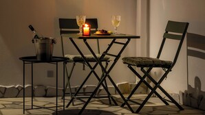 A dining area with a table, two chairs, a candle, and a bottle.