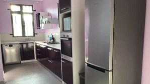 Una cocina moderna con electrodomésticos de acero inoxidable, lavavajillas y un ventanal con persianas.