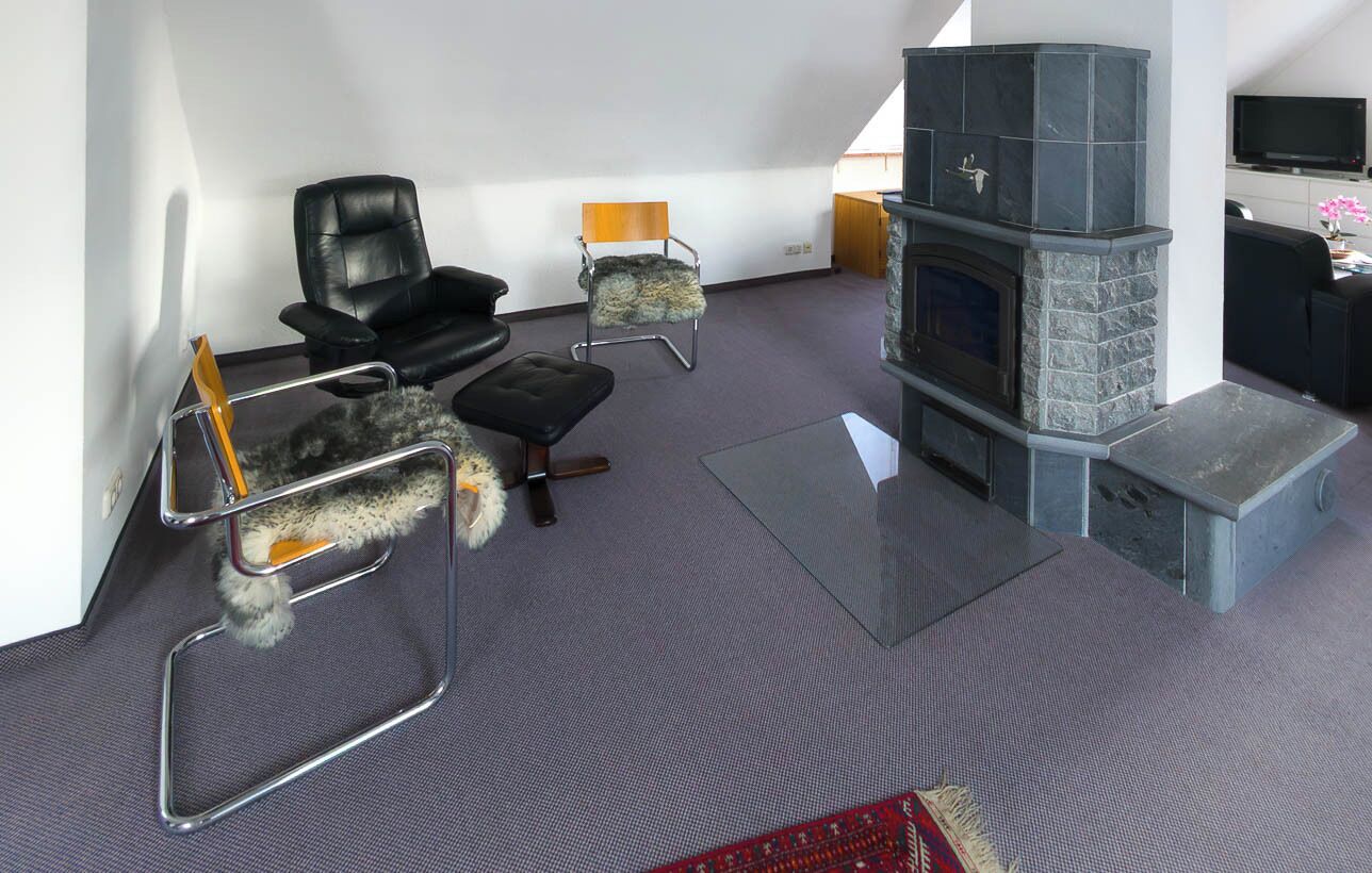 Una sala de estar moderna con chimenea de piedra, sillones de cuero, una mesa de centro de vidrio y un televisor de pantalla plana.