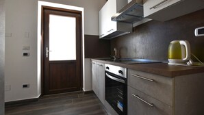 Una cocina con puerta de madera, electrodomésticos de acero inoxidable y un hervidor en la encimera.