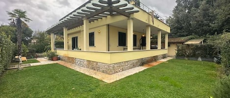 A single-story house with a covered patio, a stone foundation, and a well-maintained lawn.