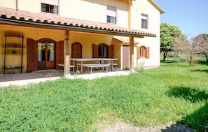 A two-story building with a covered patio, wooden shutters, and a table with benches.