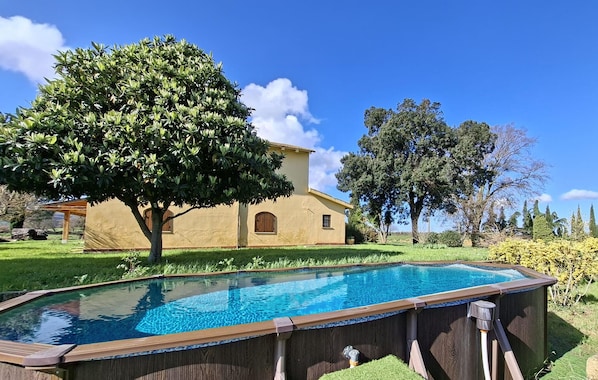 A house with a swimming pool, surrounded by a well-maintained lawn and trees.