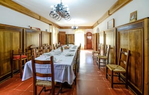 A dining room with a long table set for a meal, wooden paneling, and a chandelier.