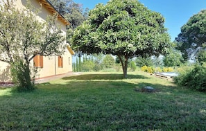 A house with a well-maintained lawn, a large tree, and a clear sky.