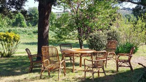 An outdoor dining area with wicker furniture and a table, surrounded by trees and greenery. - Amazing home in Manciano with private swimming pool, can be inside or outside (Manciano)