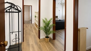 Ein Korridor mit Holzboden, einem Heizkörper, einem Blumentopf und einem schwarzen Metallregal.