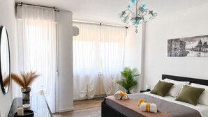 Ein modernes Schlafzimmer mit Bett, Nachttisch und einem großen Fenster mit Vorhängen.