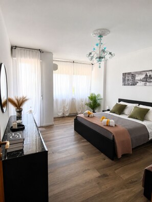 Ein modernes Schlafzimmer mit Bett, Nachttisch und einem großen Fenster mit Vorhängen.