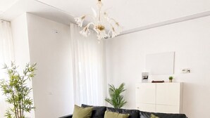 Ein modernes Wohnzimmer mit einer schwarzen Ledersofa, Holzböden, einer weißen Decke und einem Kronleuchter.