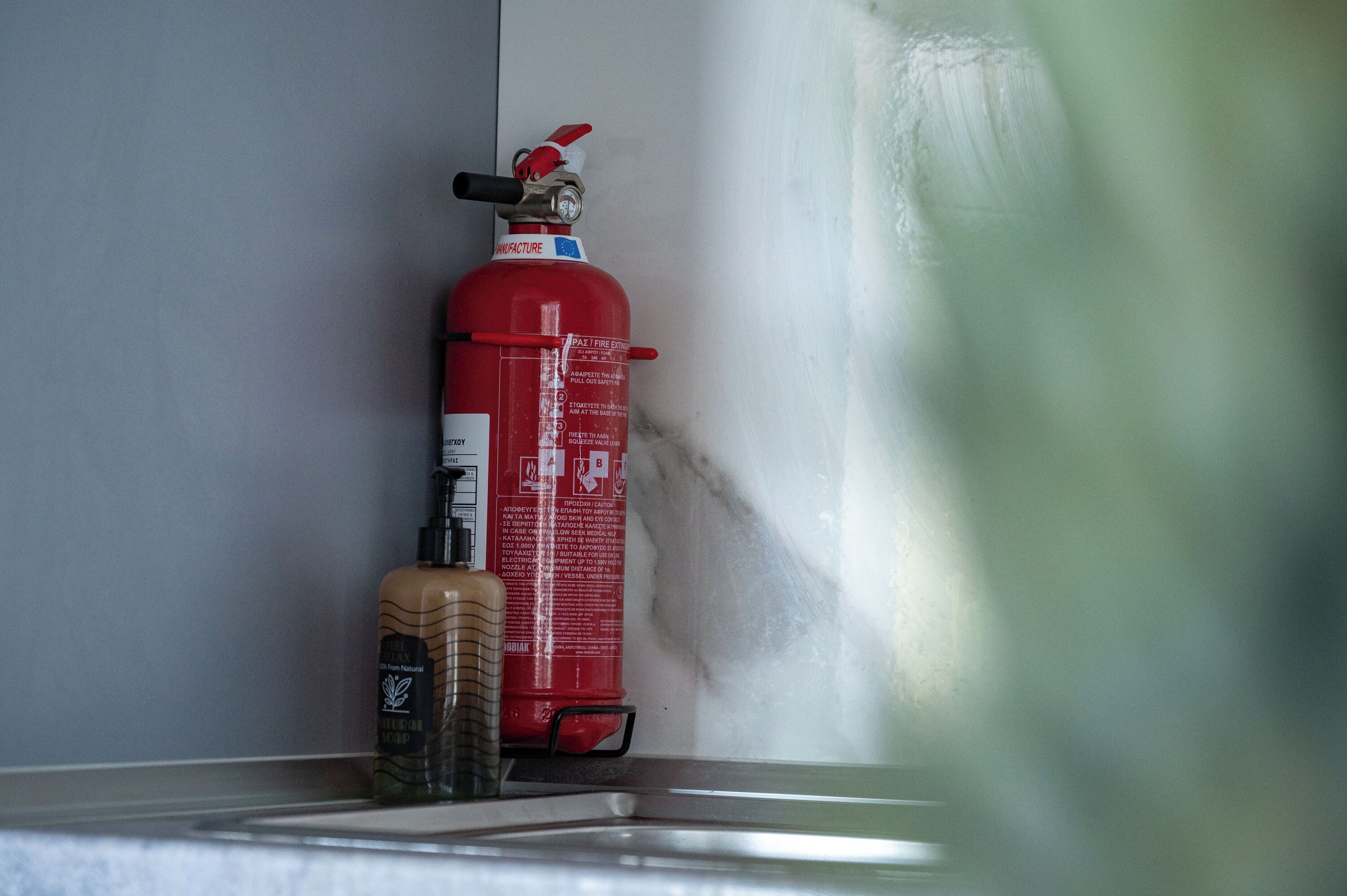 Extintor rojo montado en la pared junto a una ventana.