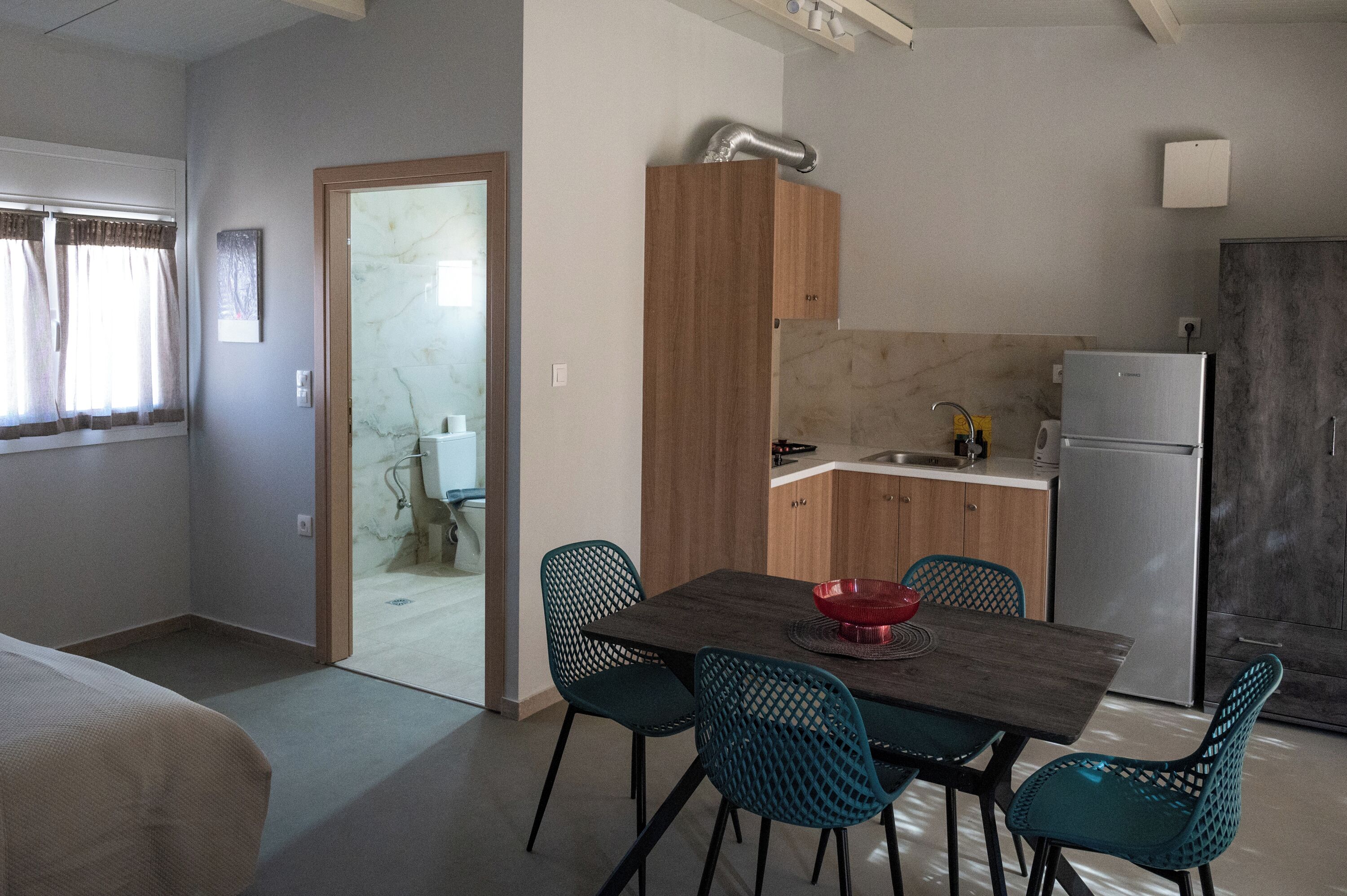 Una cuina compacta amb zona de dinar, nevera i rentaplat.