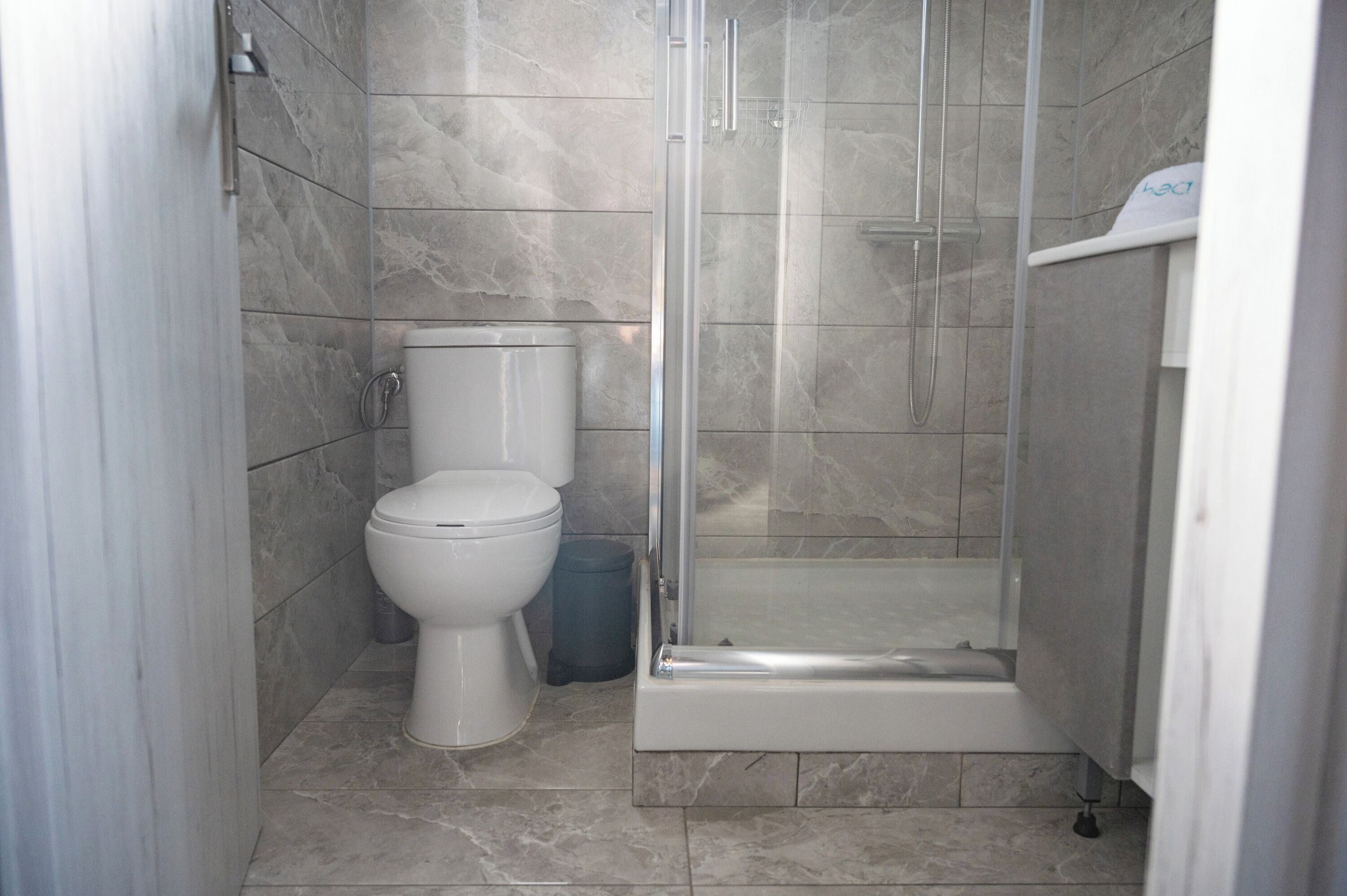 A bathroom with a toilet, a trash bin, a shower enclosure, and a bathtub.