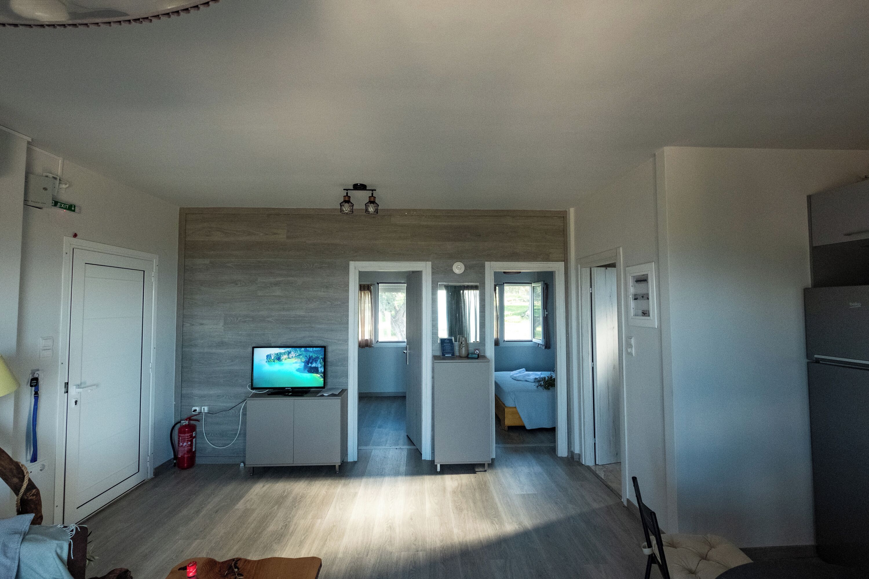 A modern interior with a television, a fire extinguisher, a sofa, and a bed in a hallway.