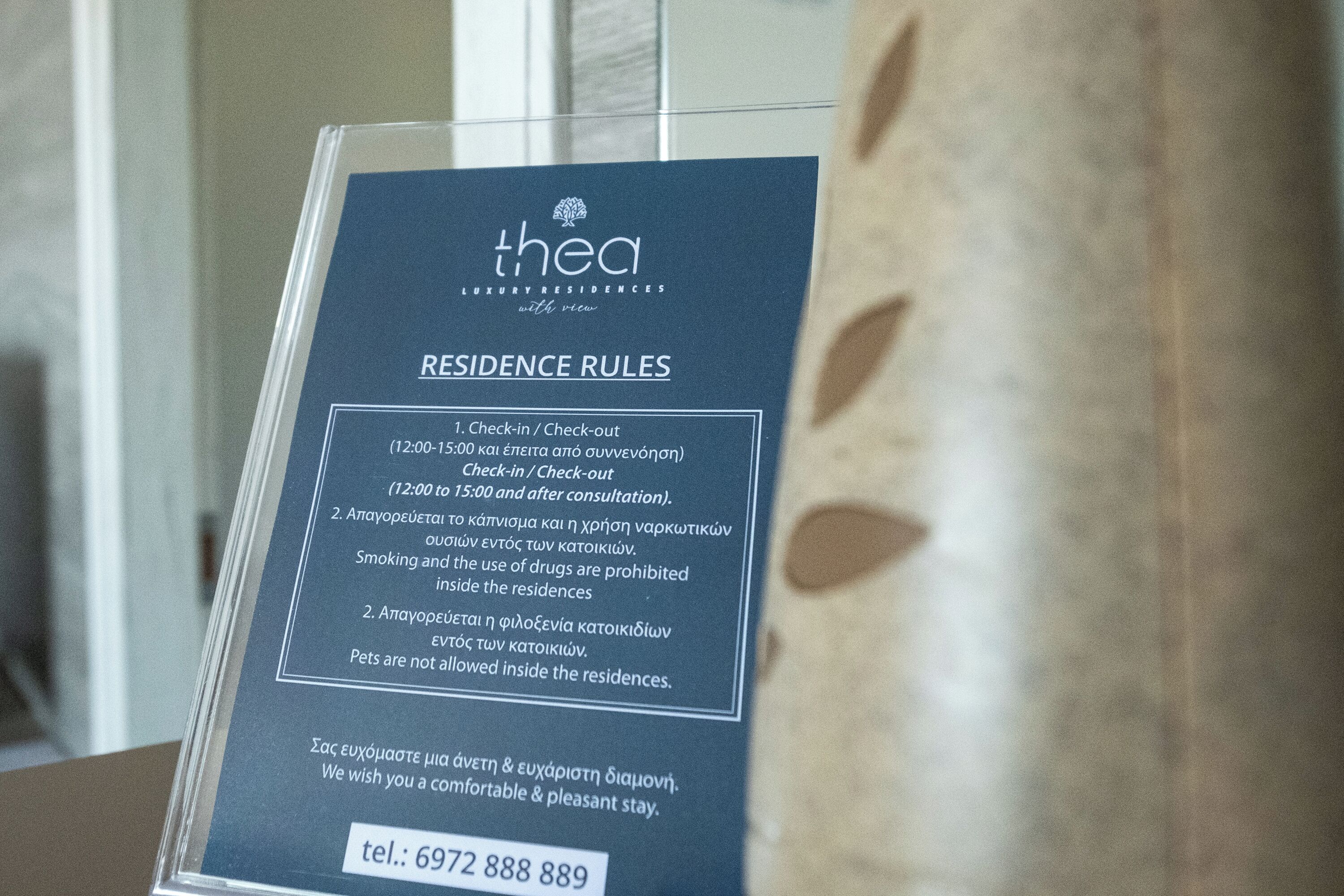 Segnaletica con le regole di soggiorno per una residenza di lusso, che include orari di check-in/check-out, politiche sul fumo e animali domestici, e un numero di contatto.
