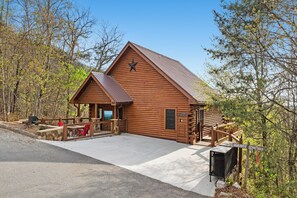 A wooden lodge with a star on the roof, a covered deck, and a stone wall.