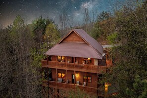 Une cabane en bois à plusieurs étages, dotée de balcons et entourée d’arbres.