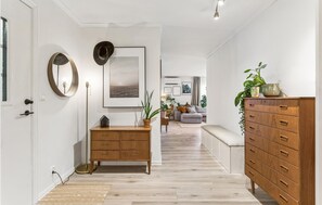 A hallway with a wooden dresser, a mirror, a framed picture, and a plant.