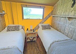 A room with two beds, a window, a wooden ladder, and a small table with a plant.