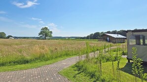 Een landelijk landschap met een geplaveid pad, een schuur en een caravan.