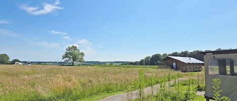 Un paisaje rural con un camino pavimentado, un granero y una caravana.