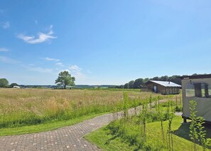 Een landelijk landschap met een geplaveid pad, een schuur en een caravan.