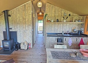 A wooden interior with a kitchen area, a fireplace, and a dining space.