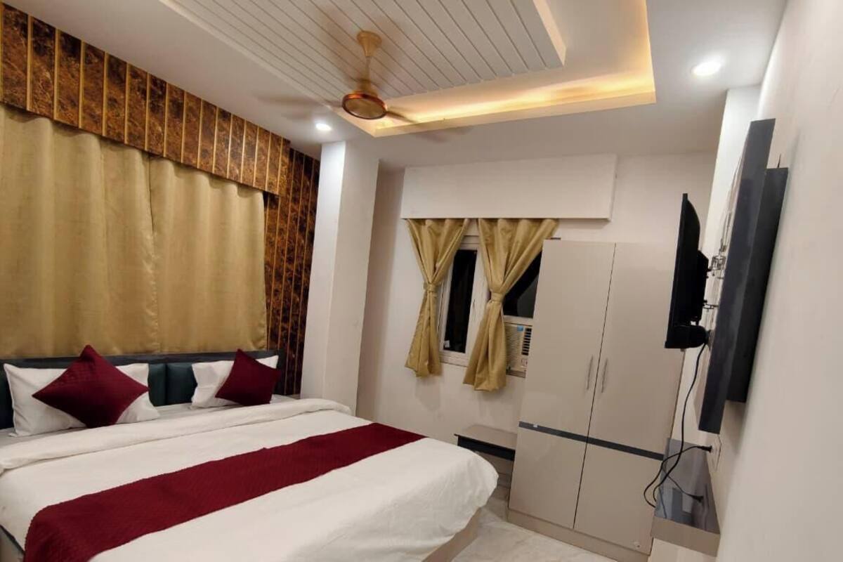 Habitación de hotel con cama, cortinas, armario, televisor y ventilador de techo.