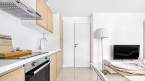 Une cuisine moderne équipée d’une cuisinière, d’un four et d’un coin repas avec un téléviseur et une table.