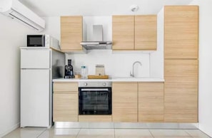 Una cocina moderna con horno empotrado, microondas y cafetera sobre la encimera.