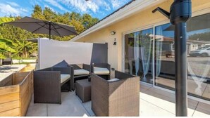 Une terrasse extérieure aménagée avec des meubles en osier, un grand parasol et une vue sur les environs.