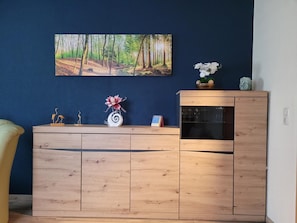 Un comptoir d’accueil en bois agrémenté d’un calendrier, d’un vase décoratif et d’un tableau représentant une forêt.