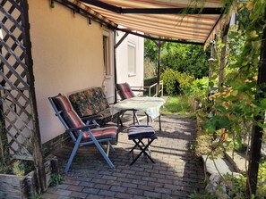 Un patio con una mesa, dos sillas, un área cubierta y una cerca de madera.