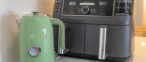 A kitchen with a green kettle and a black Ninja air fryer.