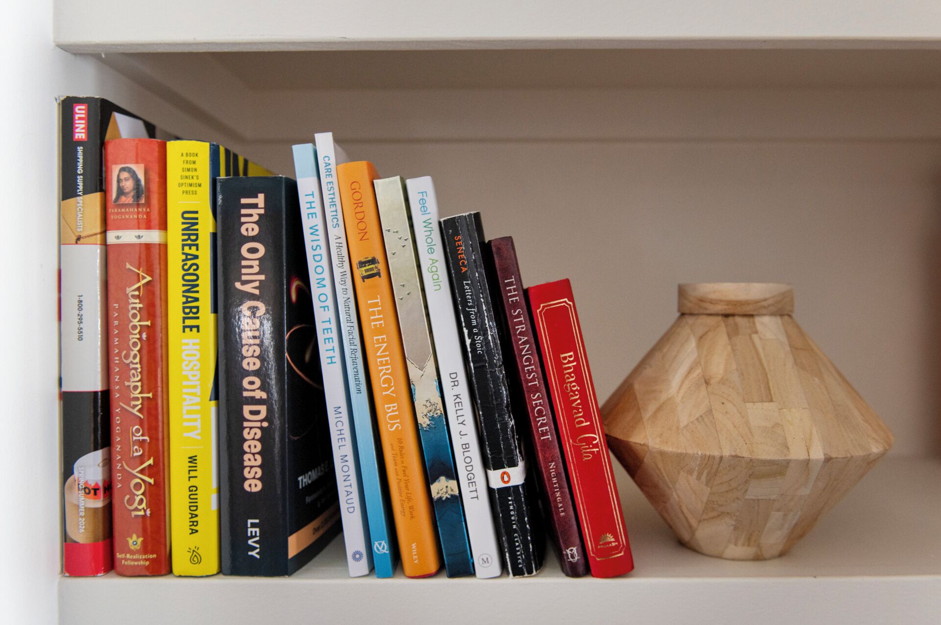 Een boekenplank met boeken en een houten vaas.