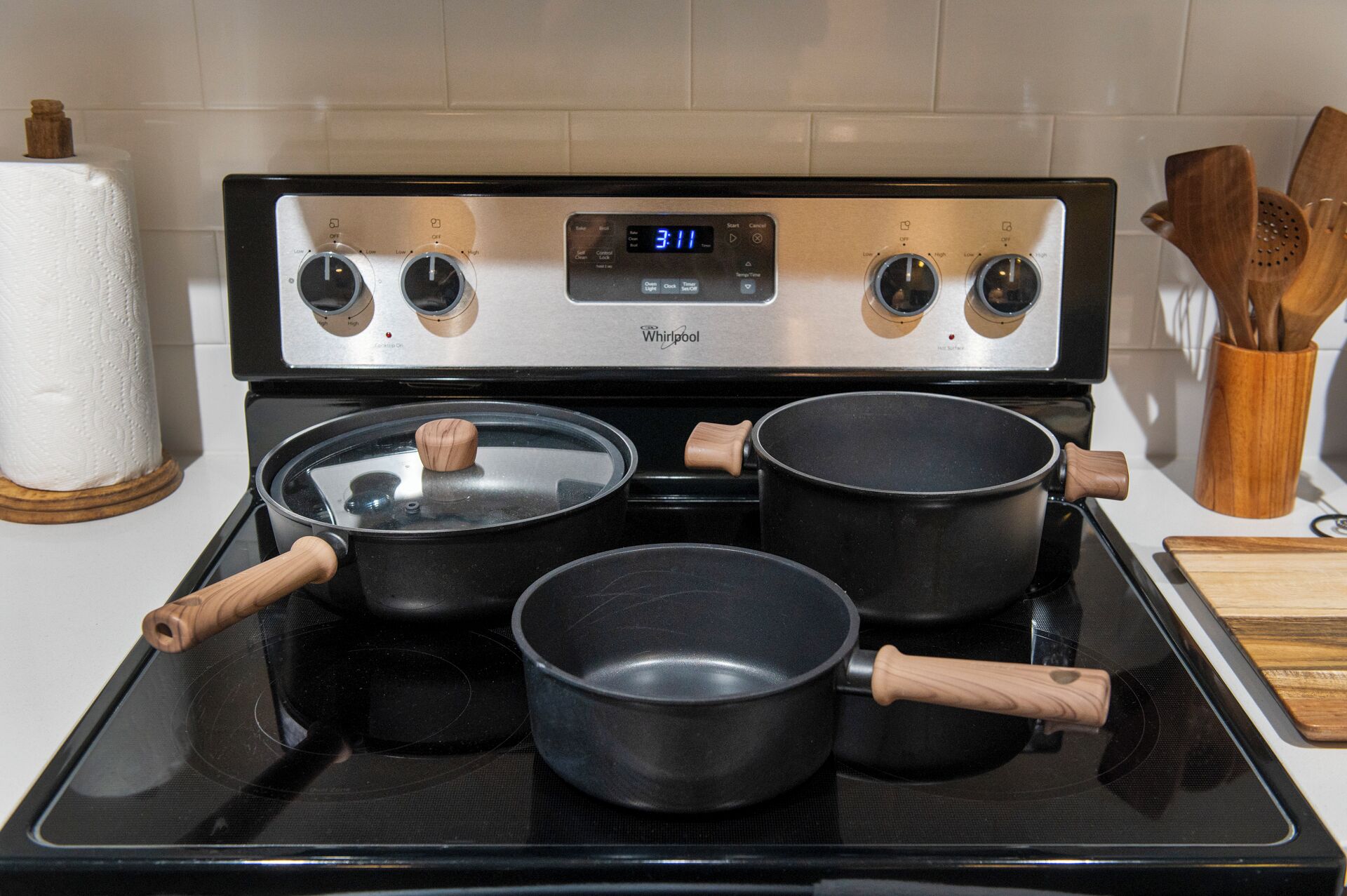 A Whirlpool stove with four pots, a timer, and a wooden utensil holder.