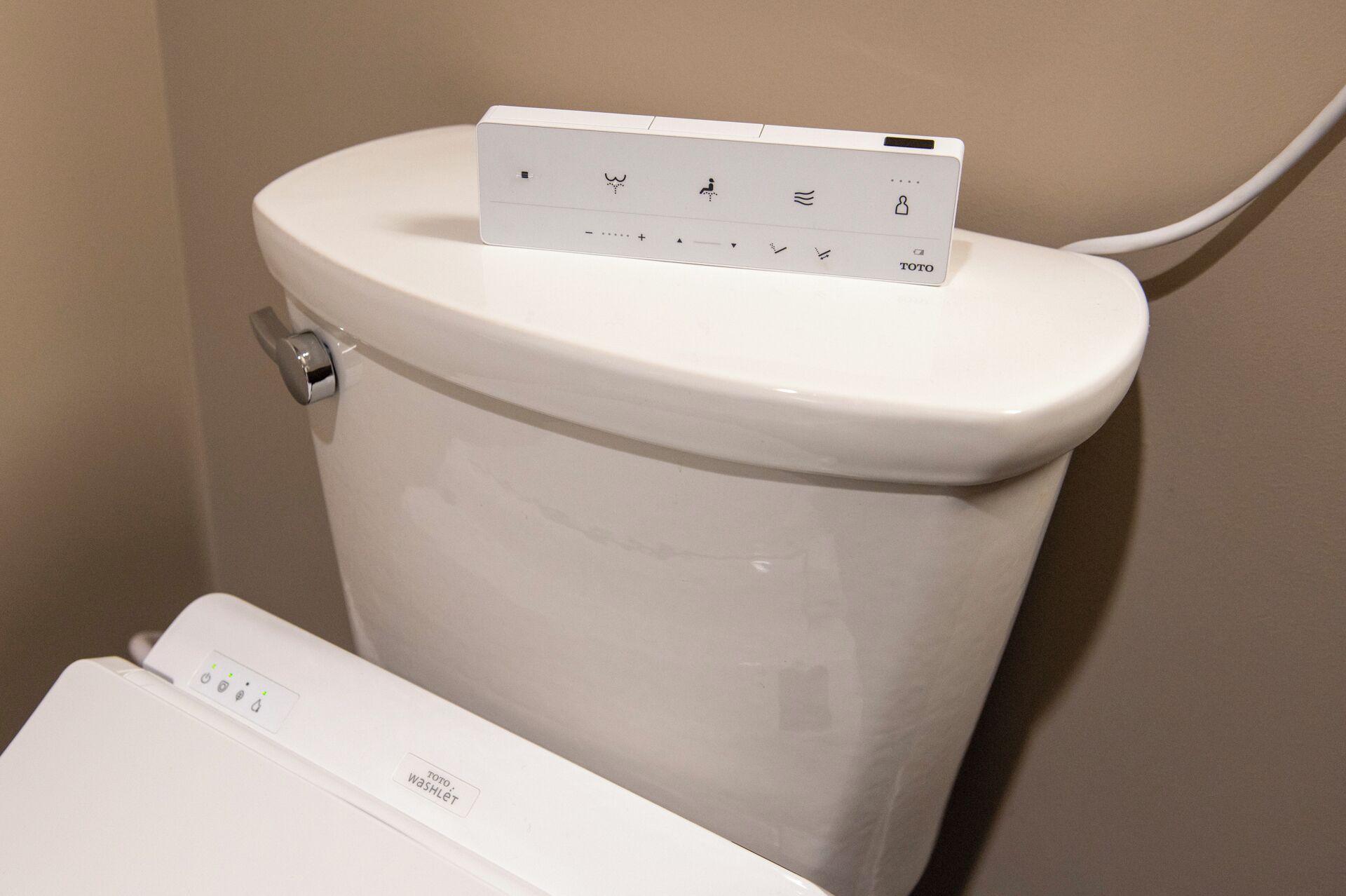 A toilet with a control panel and a hand sanitizer dispenser.