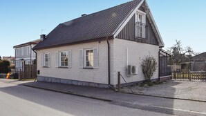 Ett tvåvåningshus med ett sluttande tak, en satellantenn och en inhägnad trädgård.