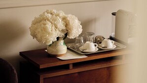 Un certificado enmarcado en la pared, un florero con flores sobre una mesa, y una bandeja con tazas de té y terrones de azúcar.