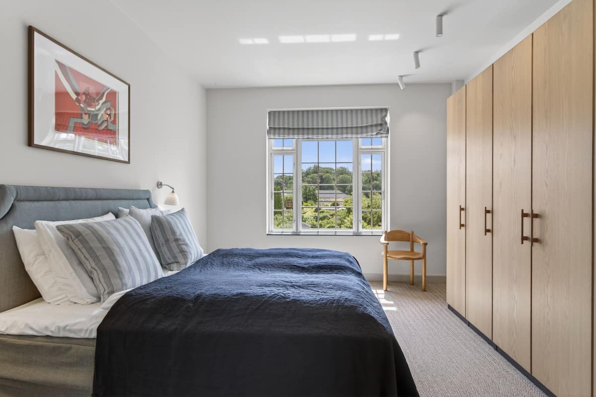 Une chambre Ă coucher avec un lit, une fenĂȘtre donnant sur un beau paysage, une armoire et une chaise.