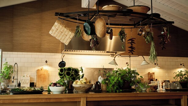 Una cocina con ollas colgantes, encimera de madera y taburetes de bar.