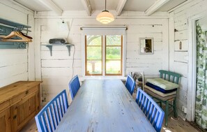 A room with a wooden dining table, blue chairs, a bench, a radio, and a window with a view of greenery. - 1 bedroom gorgeous home in Köpingsvik (Köpingsvik)